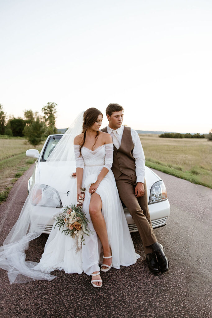 bride and groom leaning on car